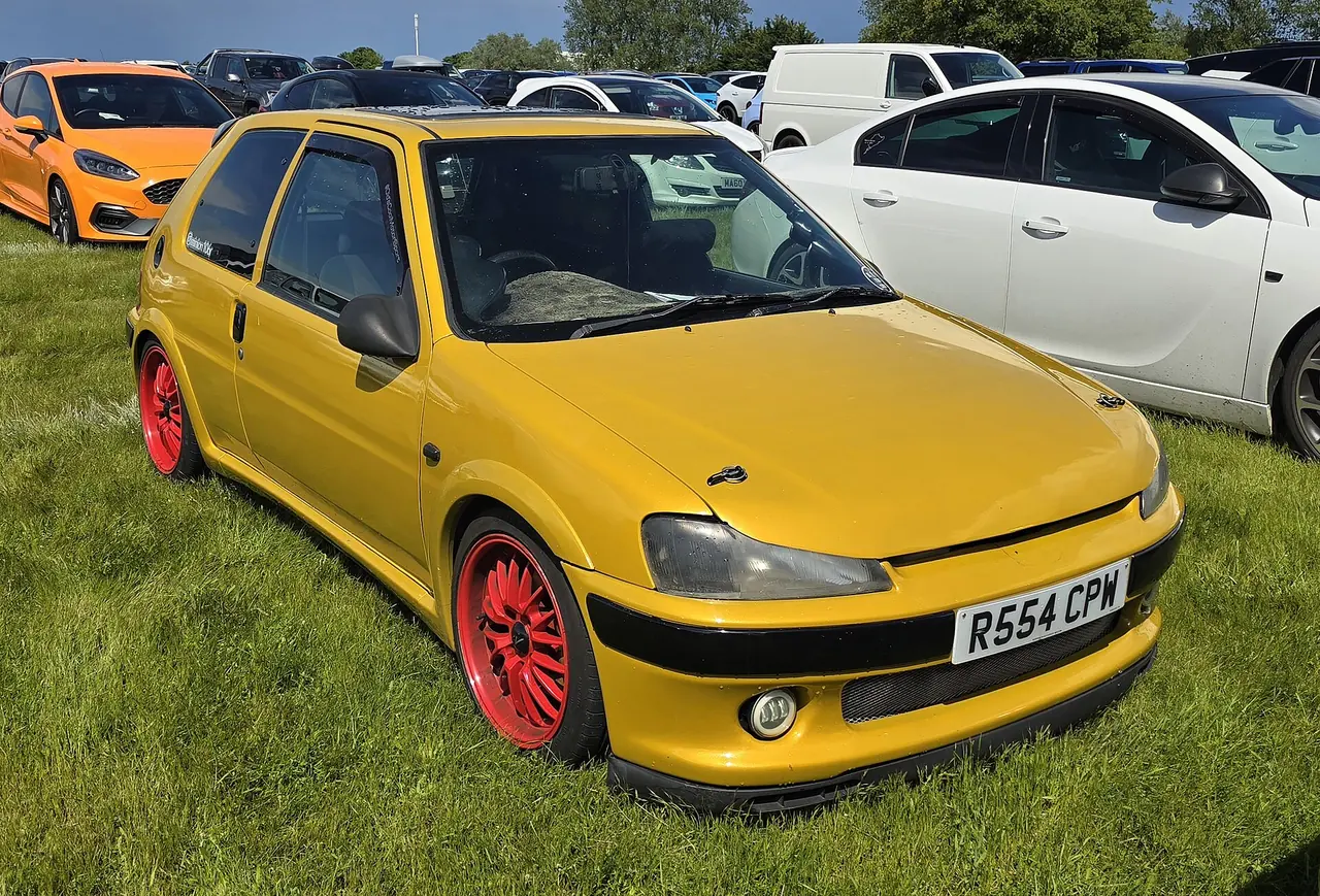 Yellow Peugeot 106 Look with black lower bumper and red wheels.
